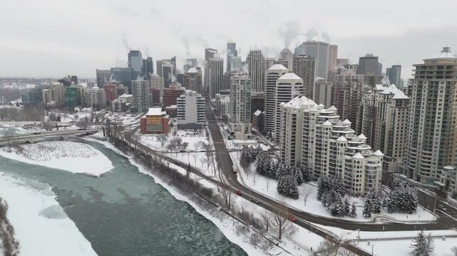 Winter city tracking shot tower blocks with heat ventilation HVAC systems overlooking icy river in Calgary Alberta Canada
