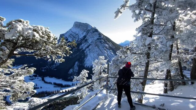 Banff Alberta Canada, January 09 2025: Tourist taking pictures overlooking winter alley on Tunnel Mountain Hiking Trail.
