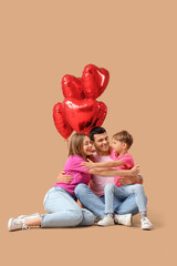 Little boy with his parents and balloons hugging on beige background. Valentine's Day celebration