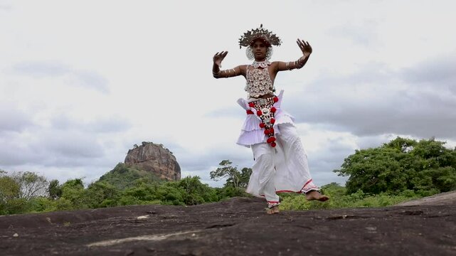  A Ves Dancer, also known as a Kandyan Dancer or Up Country Dancer performs at Sigiriya in Sri Lanka. In the background stands Sigiriya Rock.