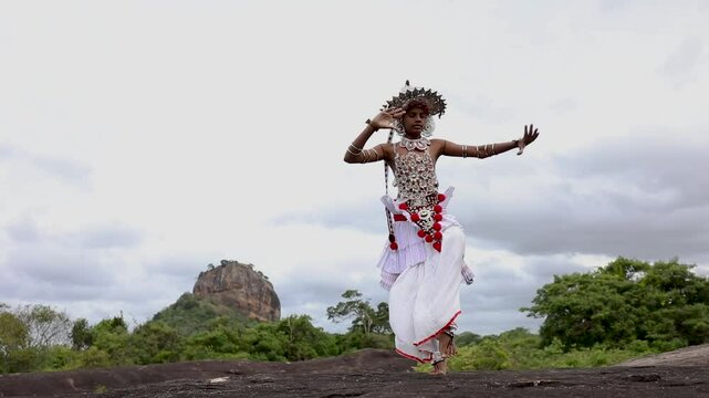  A Ves Dancer, also known as a Kandyan Dancer or Up Country Dancer performs at Sigiriya in Sri Lanka. In the background stands Sigiriya Rock.
