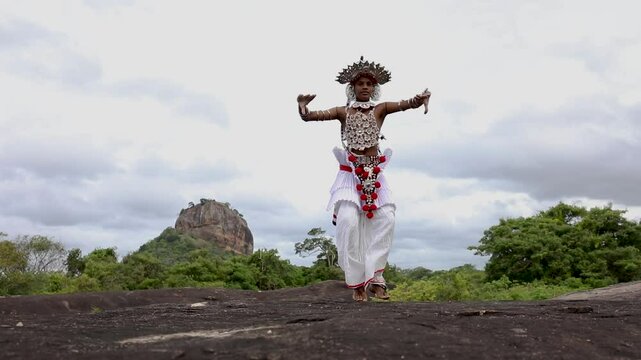 A Ves Dancer, also known as a Kandyan Dancer or Up Country Dancer performs at Sigiriya in Sri Lanka. In the background stands Sigiriya Rock.