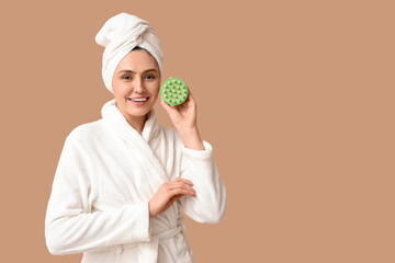 Happy young woman with hair scalp massager on brown background