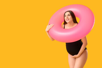 Young pregnant woman with inflatable ring on yellow background. Travel concept