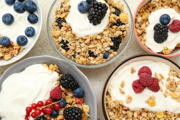 Bowls of tasty granola with yogurt on grunge background, closeup