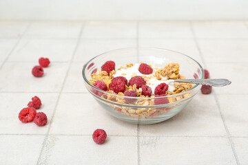 Bowl of tasty granola and yogurt on light tile background