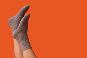 Legs of young woman in grey cotton socks on orange background