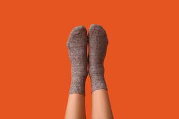 Legs of young woman in grey cotton socks on orange background