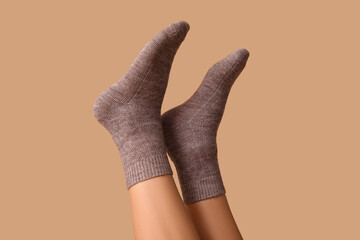 Legs of young woman in grey cotton socks on brown background