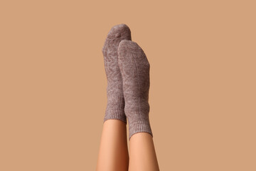 Legs of young woman in grey cotton socks on brown background