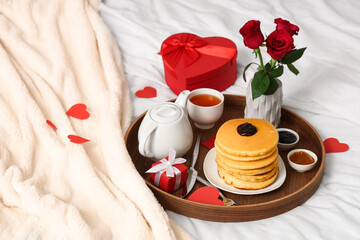 Tray with breakfast, roses and gifts for Valentine's Day on bed