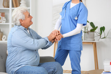 Female doctor with mature man holding hands at home