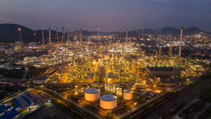 Obraz premium Oil Refinery plant at sunset. Gas Chemical Equipment Prodiction import export Concept, Crude Oil Refinery Plant Steel Pump Pipe line and Chimney and Cooling tower, Chemical Petrochemical