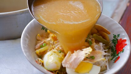 Chicken soup with shredded chicken, chicken feet, eggs, sliced cabbage, vermicelli in broth. Indonesia food.