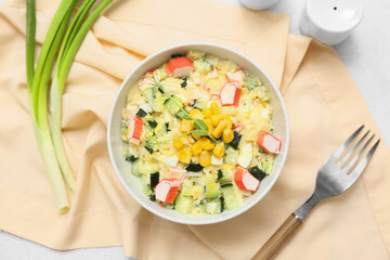 Bowl of salad with crab sticks, corn and cucumber on white background