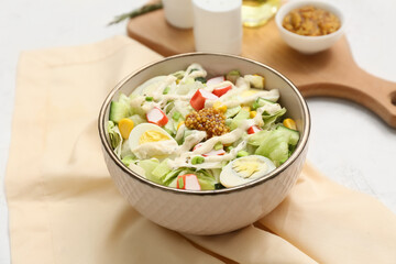 Bowl of salad with crab sticks, corn, iceberg leaves, quail eggs and cucumber on napkin