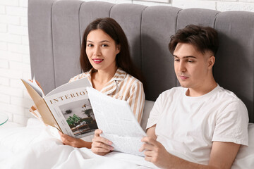Young couple reading magazines together in bed