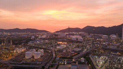 Obraz premium Oil Refinery plant at sunset. Gas Chemical Equipment Prodiction import export Concept, Crude Oil Refinery Plant Steel Pump Pipe line and Chimney and Cooling tower, Chemical Petrochemical