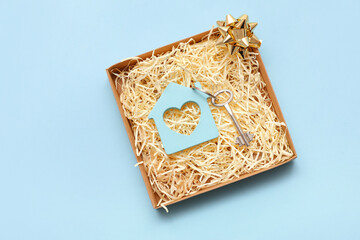 Gift box with house figure and key on blue background