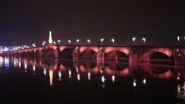 Pan view of Jacques-Gabriel Bridge in Blois, France with street lights and vehicles passing by at night time.