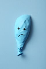 Balloon with drawn sad face on blue background