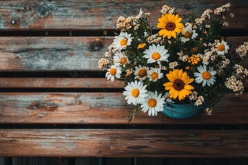 Obraz premium Daisies and sunflowers in a teal pot on wood