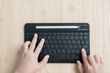 Female hands are typing text using a small black external keyboard.