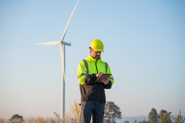 Engineer wearing uniform inspection and survey work in wind turbine farms rotation to generate electricity energy. Maintenance engineer working in wind turbine farm.