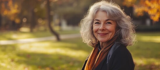 Happy elderly Caucasian woman enjoying sunny day in autumn park surrounded by colorful leaves, exhibiting positive mindset and healthy lifestyle.