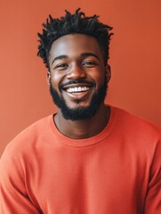 Fototapeta premium Cheerful African Man with Beaming Smile Posing in Front of Orange Background, Large Empty Copy Space for Text, Young Adult, Trendy Hairstyle