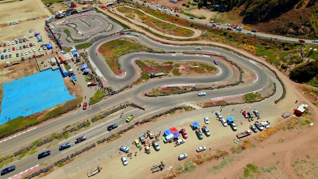 Aerial view establishing a drifting event on a sunny day, clandestine and youth events, leisure on a small track. Ritoque, Chile
