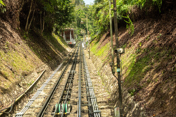 Penang Hill railway tracks leading into tunnel surrounded by lush greenery, steep incline funicular...