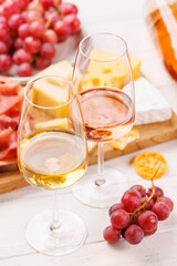 A delectable arrangement of various cheeses, fresh grapes, prosciutto and wine