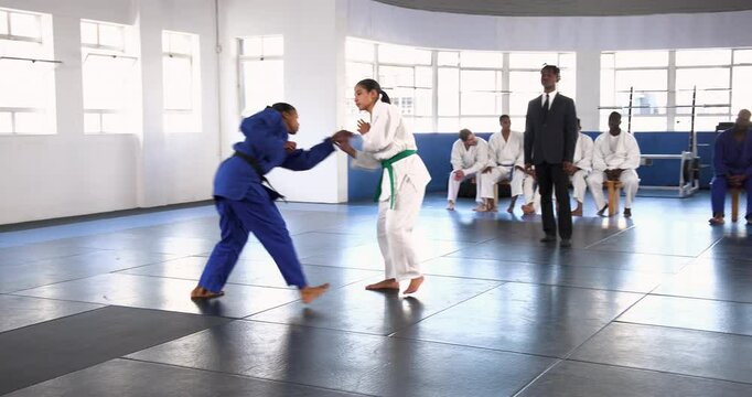 Practicing judo, two athletes sparring on mat in martial arts school