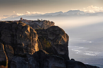 Travel to Meteora. The Monastery of Holy Trinity photographed in amazing sunset light with mountains in foreground. Travel to Orthodox iconic place of Meteora in Greece.