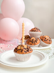 Chocolate chip muffins with birthday candle and pink balloons in background. Birthday concept