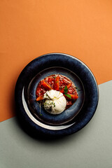 Burrata cheese served on plate with Cherry Tomatoes and herbs