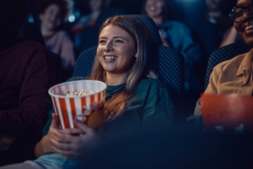Happy woman enjoying during film screening at movie theatre.