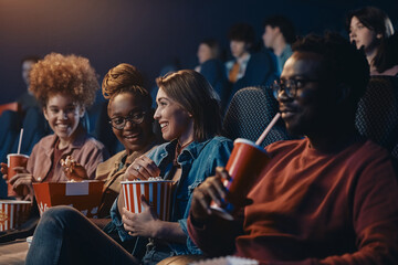 Happy woman and her female friends watching movie in theater.