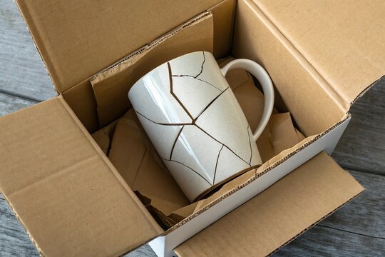 Broken ceramic cup in delivery box. Fragile item damag