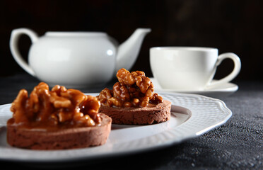 Chocolate brownie. Walnuts are on top of the cake. The concept of breakfast. The kettle is out of focus.Black background.
