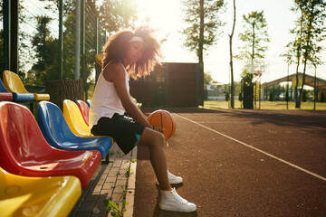 Attractive confident young sportswoman with basketball ball in hands