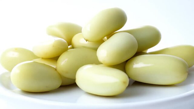 360-degree rotation video, high-key lighting, a mound of lima beans, their smooth white curves inviting and soft