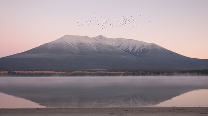 Mountain reflection in calm lake at sunrise with birds flying.