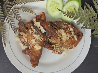 Crispy fried duck served on a white plate, split into two halves. Topped with crunchy crumbs for...