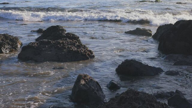 Slow motion clip of waves crashing against rocks on the shore at Muir Beach in Northern California. Captures serene coastal beauty, natural textures, and waves. Perfect for travel and nature themes.