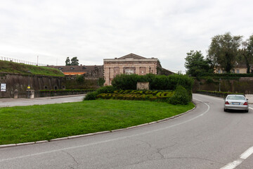 A view of the fortified entrance of Peschiera del Garda, Italy, with its imposing walls and gate. A car drives along the road leading to the fortress