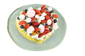 Heart-shaped cake decorated with red fruits and meringue. White background. Valentine's Day. Copy space.