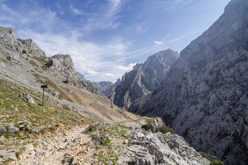 A mountain range with a clear blue sky and a few clouds. Cares Route.