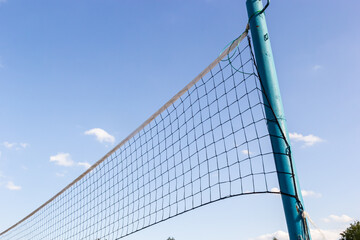 Bright blue sky highlights a volleyball net at a beach during a sunny afternoon